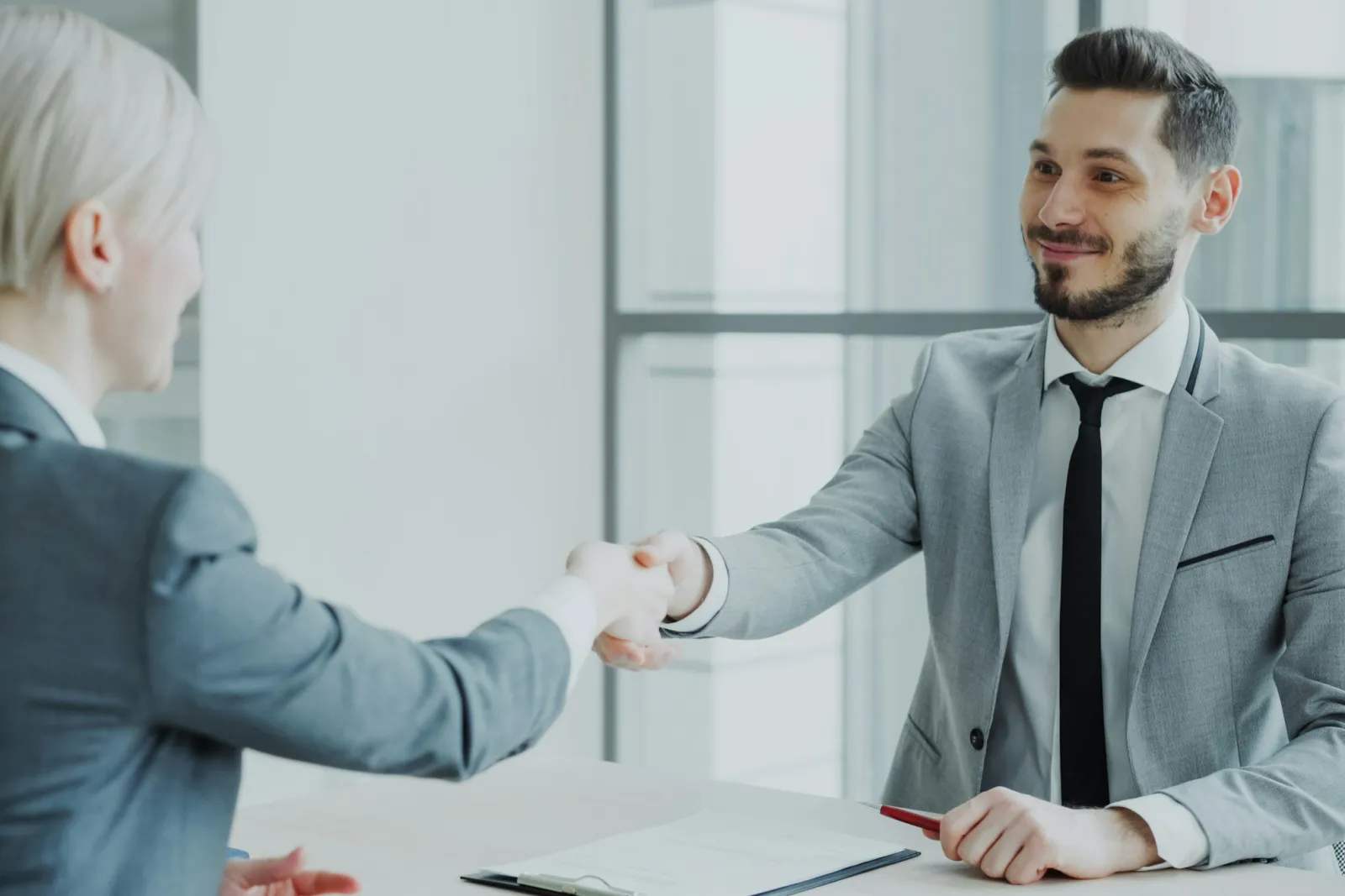 Two business professionals shaking hands across a table
