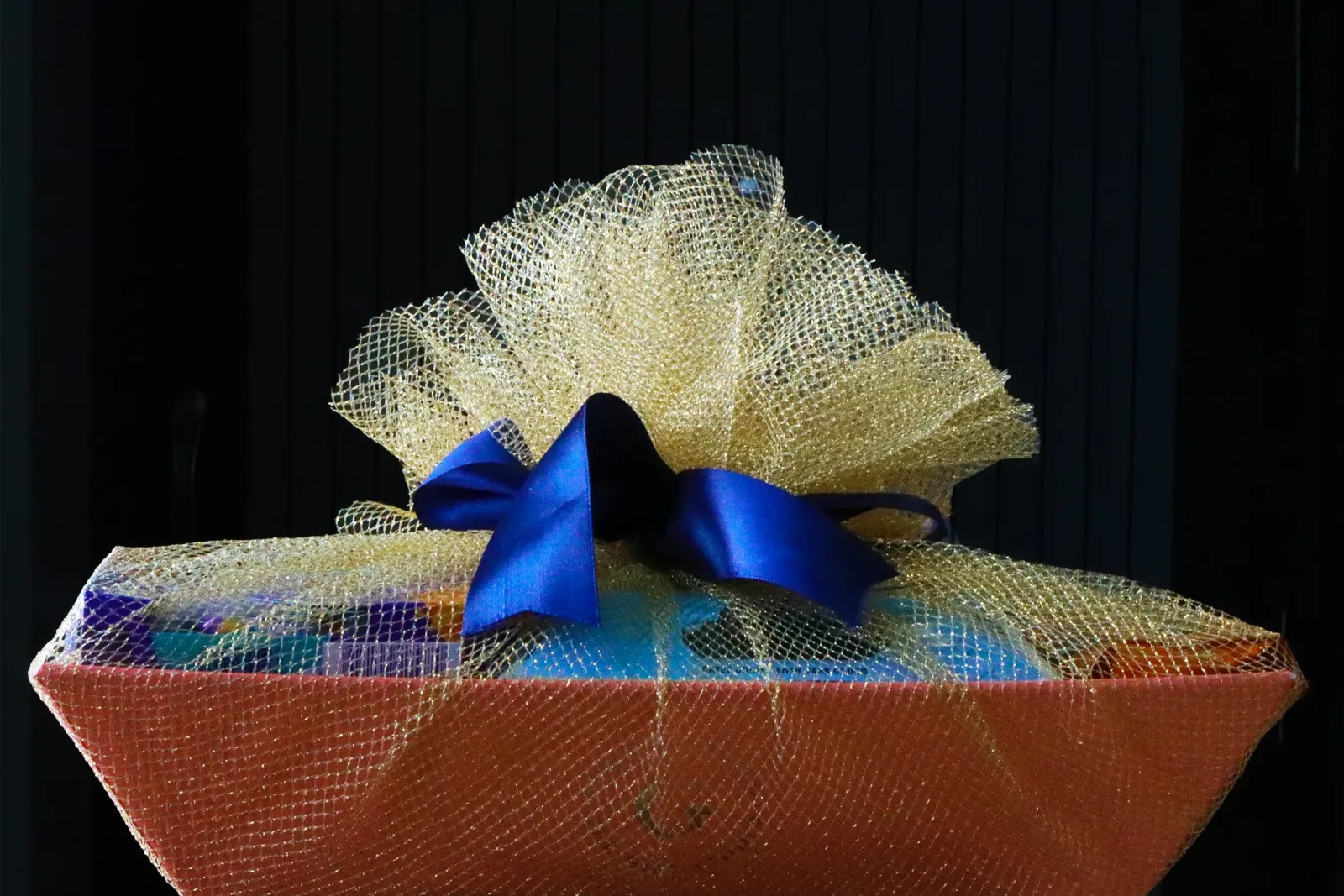 A decorative gift hamper wrapped in gold netting with a blue ribbon