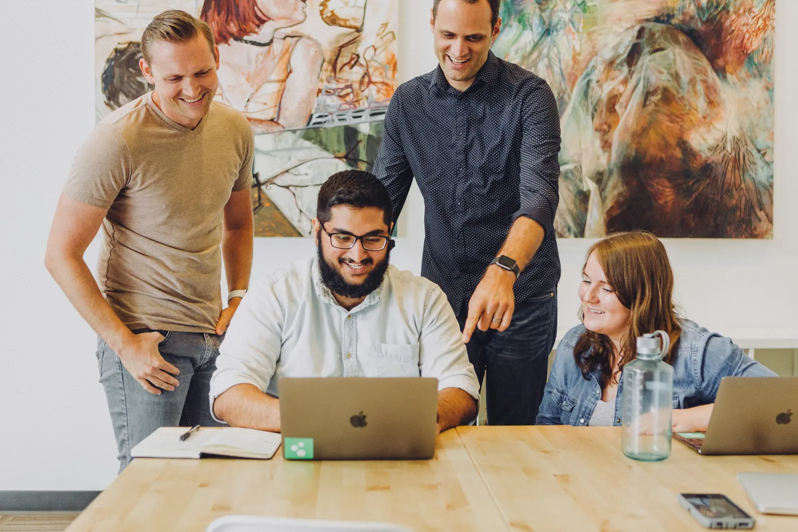 A small team gathered around a laptop reviewing work together